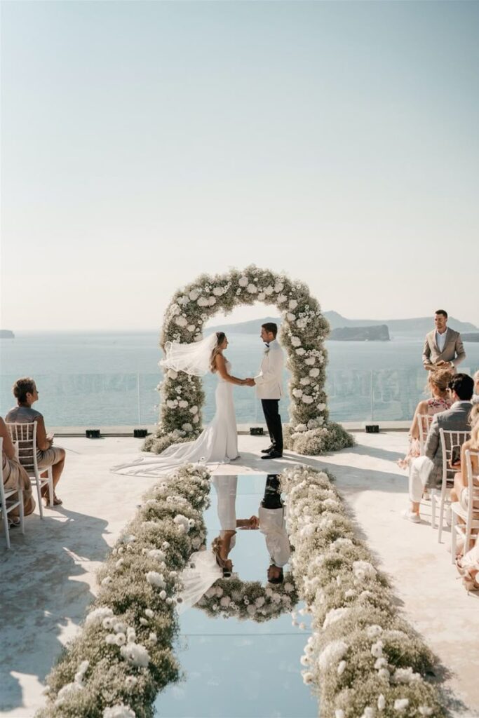 Romantic outdoor wedding ceremony in Crete with floral arch, bride and groom, and guests – Wedspace coordination