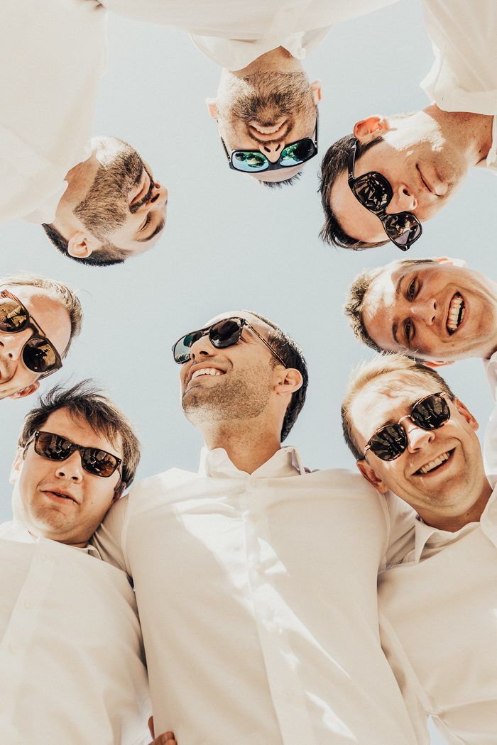 A joyful bachelor party in Crete with a group of happy men in sunglasses, smiling and hugging in a fun outdoor celebration — part of Celebrations and Events in Crete.