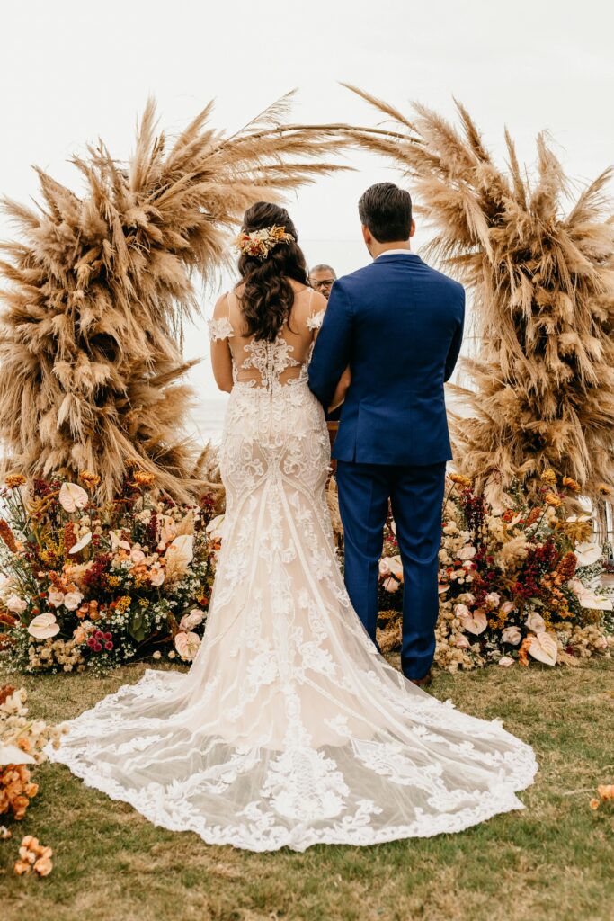 Bride and groom standing before a rustic circular wheat arch – emotional wedding moment in Crete by Wedspace
