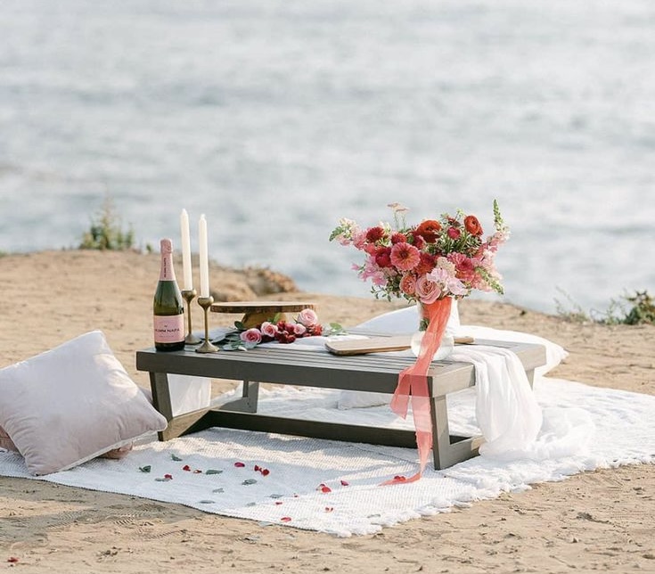Intimate proposal setup in Crete by the sea — small table with candles, champagne, flowers, and cushions ready for the perfect proposal moment.