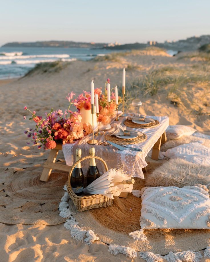 Beautiful sunset picnic proposal by the sea in Crete — decorated with champagne bottles, candles, flowers, and pillows for a perfect proposal setting.