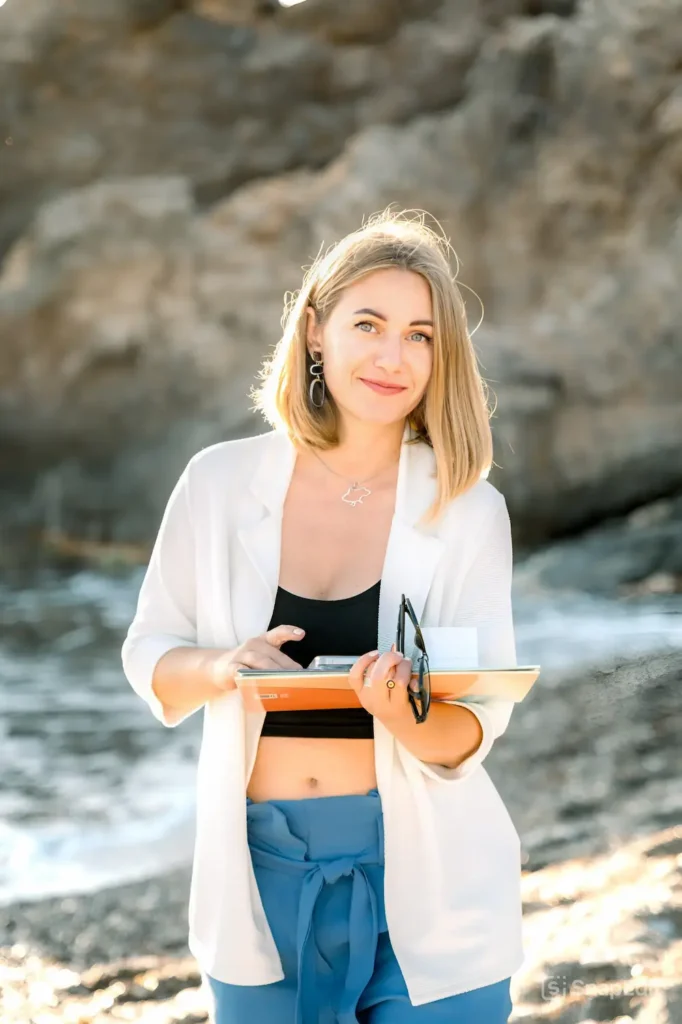 Wedding and event designer in Crete standing by the sea and cliffs, planning intimate celebrations with care and clarity.