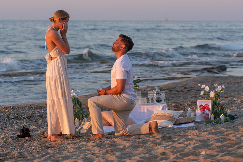 Keno proposing to Romina on bended knee on a sandy beach in Rethymno during sunset by WedSpace Crete
