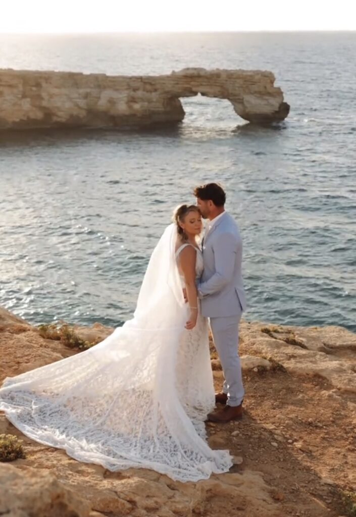 Bride and groom standing on a rocky coast near a natural sea arch  on Crete, Spilies
