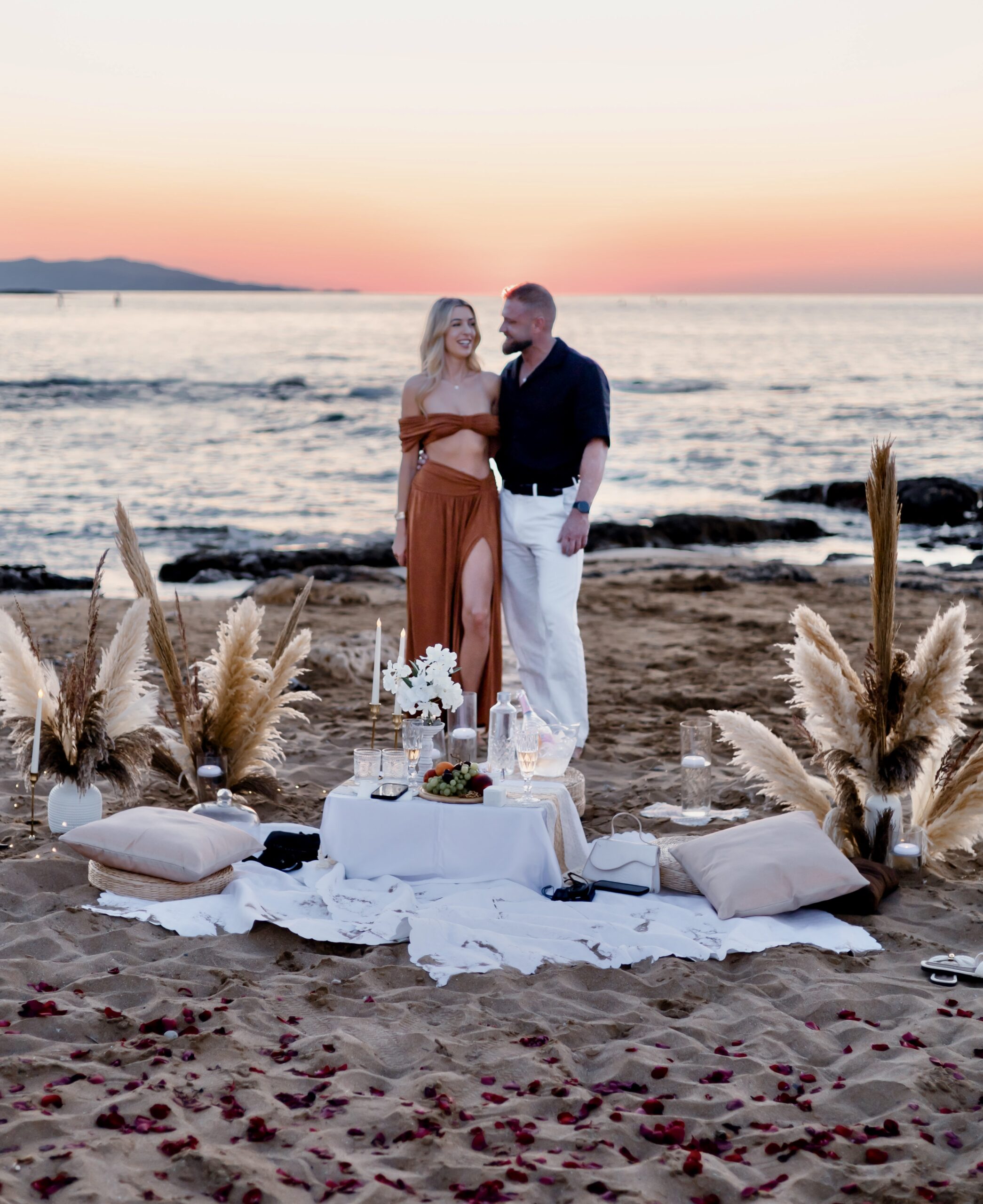 Boho style beach marriage proposal setup with pampas grass and picnic decor in Malia, Crete by WedSpace.⁠