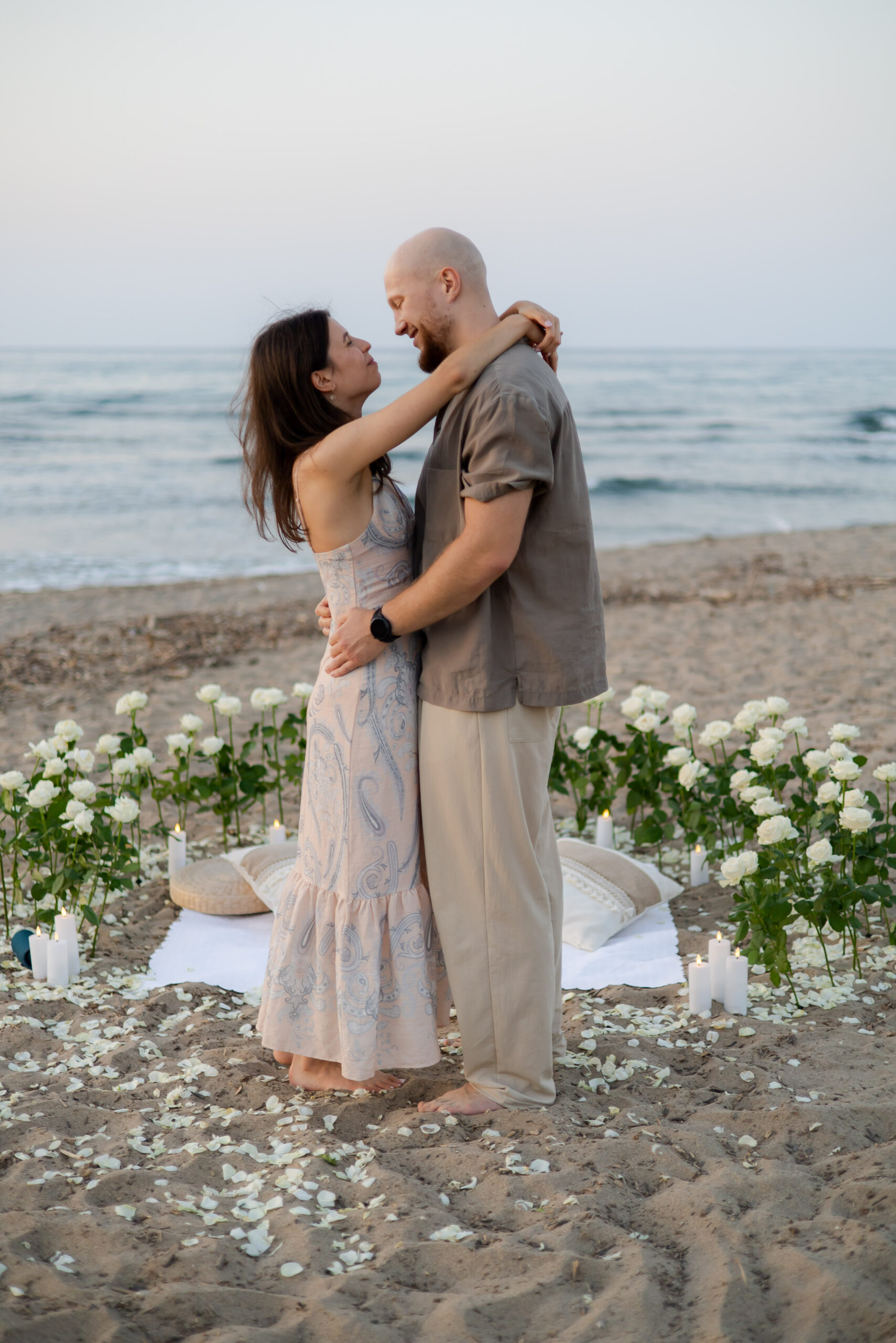 Semicircle of white roses for a beach marriage proposal at Episkopi Beach in Crete by WedSpace.