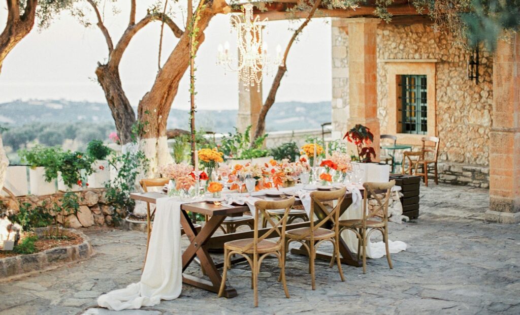 ⁠Elegant rustic wedding table setup with floral arrangements and chandelier for an intimate celebration at Agreco Farm in Crete designed by WedSpace
